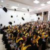 estudiantes en acto académico celebran el fin de su carrera con birrete al aire.